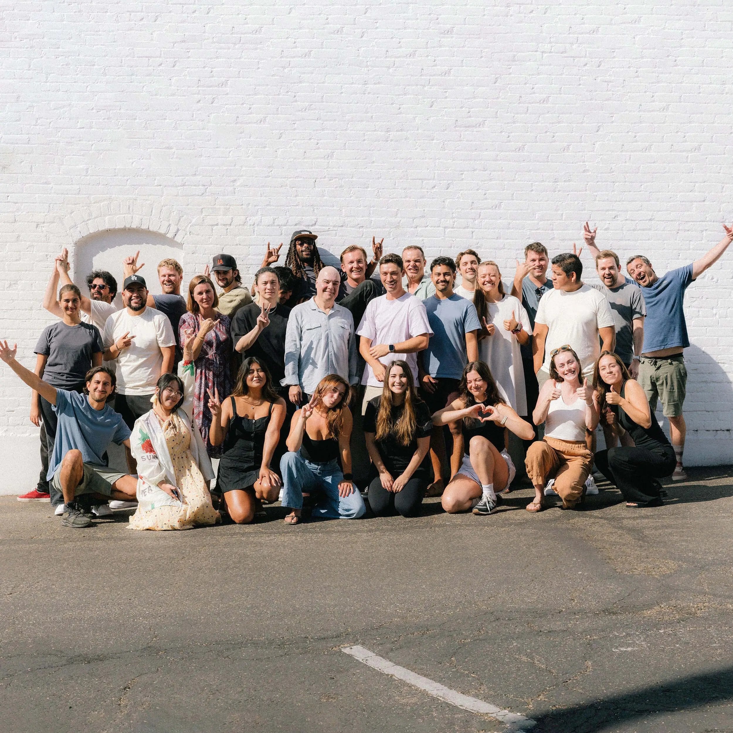 A group photograph of Vidlogix employees on the side of building on a sunny day.